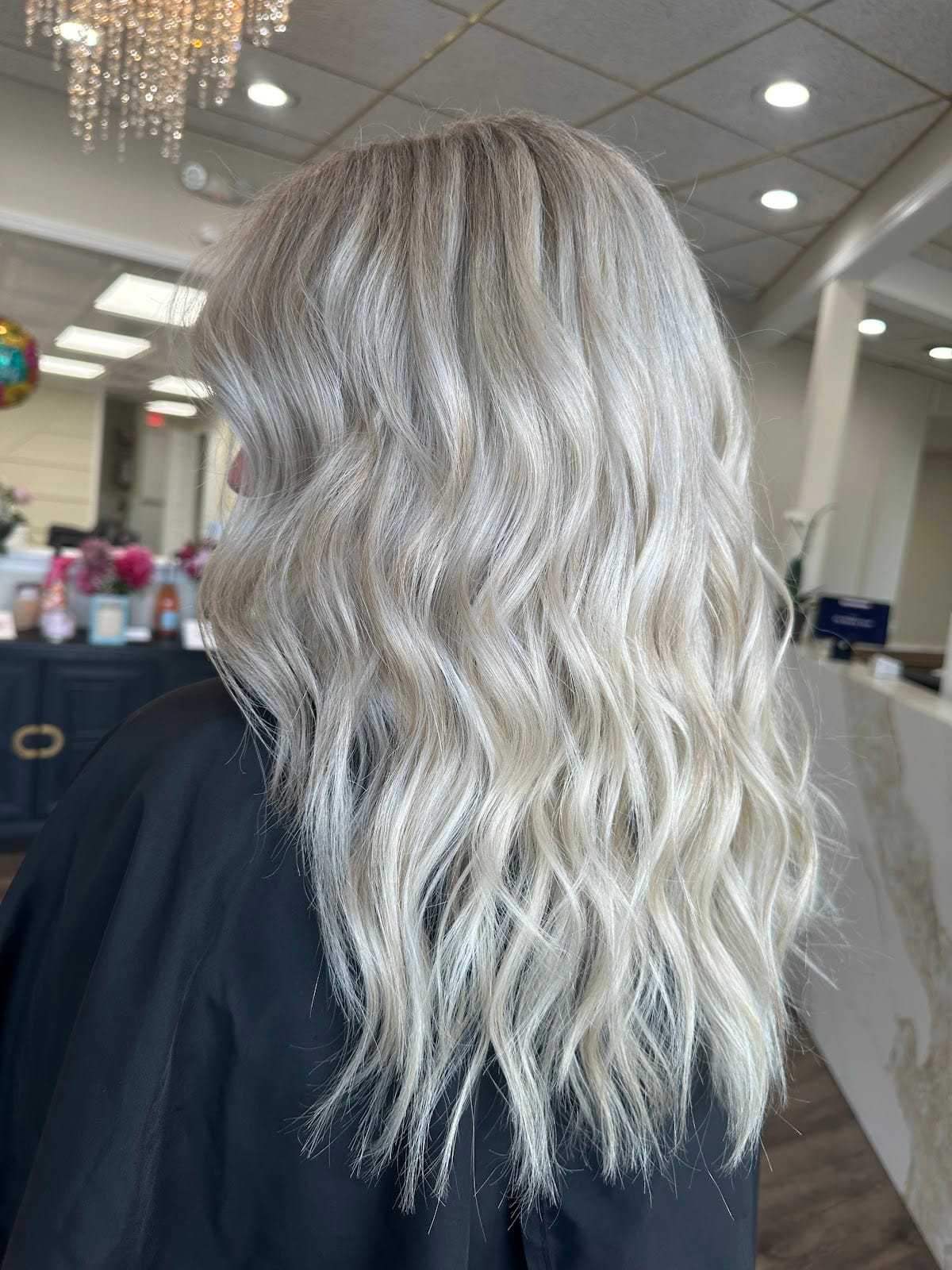 Wavy blonde hair with highlights in a modern salon setting.